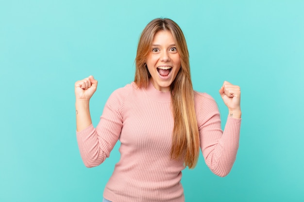 Mujer bonita joven que se siente conmocionada, riendo y celebrando el éxito