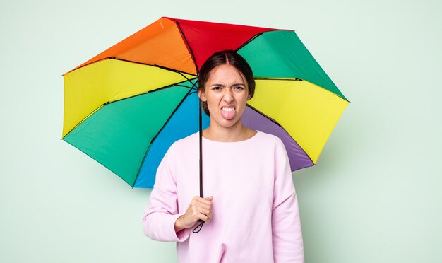 Mujer bonita joven que se siente disgustada e irritada y con la lengua fuera. concepto de paraguas