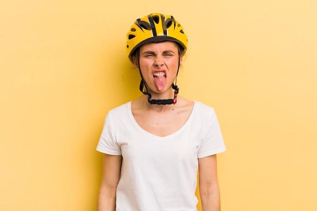 Mujer bonita joven que se siente disgustada e irritada y saca la lengua del concepto de bicicleta