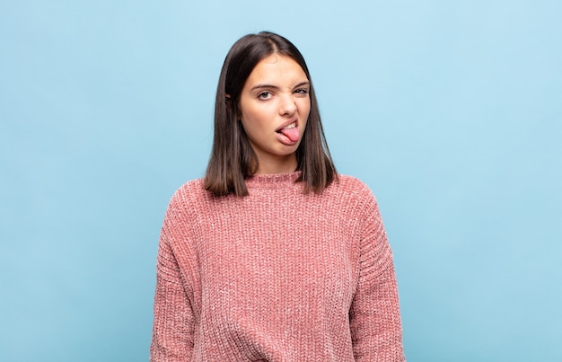 Mujer bonita joven que se siente disgustada e irritada, sacando la lengua, disgustando algo desagradable y asqueroso