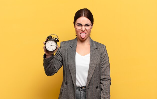 Mujer bonita joven que se siente disgustada e irritada, sacando la lengua, disgustando algo desagradable y asqueroso