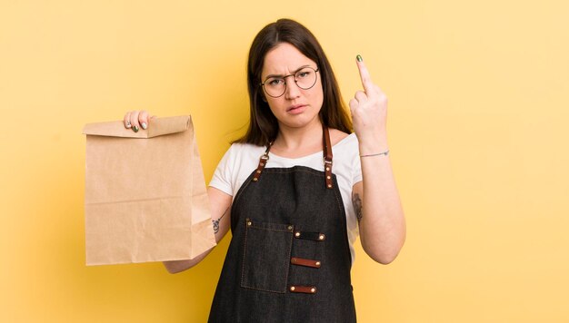 Mujer bonita joven que se siente enojada, molesta, mensajero de comida rápida rebelde y agresivo