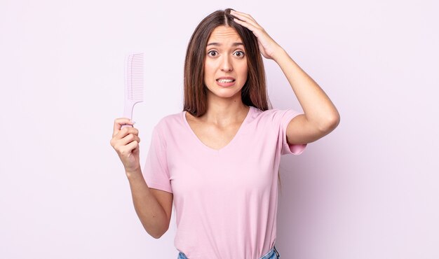 Mujer bonita joven que se siente estresada, ansiosa o asustada, con las manos en la cabeza. concepto de peine de pelo