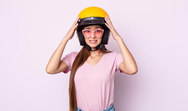 Foto mujer bonita joven que se siente estresada, ansiosa o asustada, con las manos en la cabeza. motociclista y casco