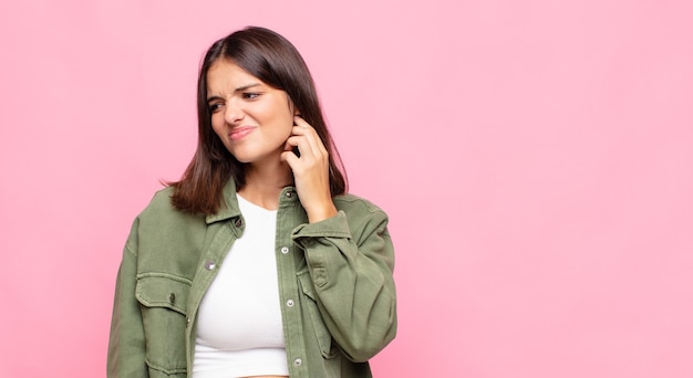 Mujer bonita joven que se siente estresada, frustrada y cansada, frotando el cuello doloroso, con una mirada preocupada y preocupada