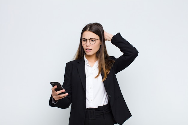 Mujer bonita joven que se siente estresada, preocupada, ansiosa o asustada, con las manos en la cabeza, aterrorizada por un teléfono móvil