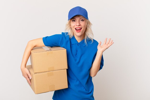 Mujer bonita joven que se siente feliz y asombrada por algo increíble. concepto de entrega de paquetes