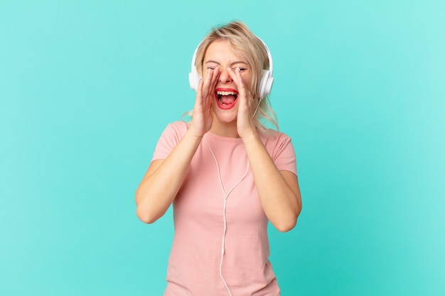 Mujer bonita joven que se siente feliz, dando un gran grito con las manos al lado de la boca. escuchando musica concepto