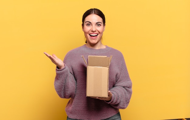 Mujer bonita joven que se siente feliz, emocionada, sorprendida o conmocionada, sonriendo y asombrada por algo increíble