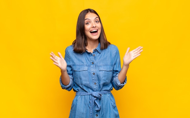 Mujer bonita joven que se siente feliz, emocionada, sorprendida o conmocionada, sonriendo y asombrada por algo increíble