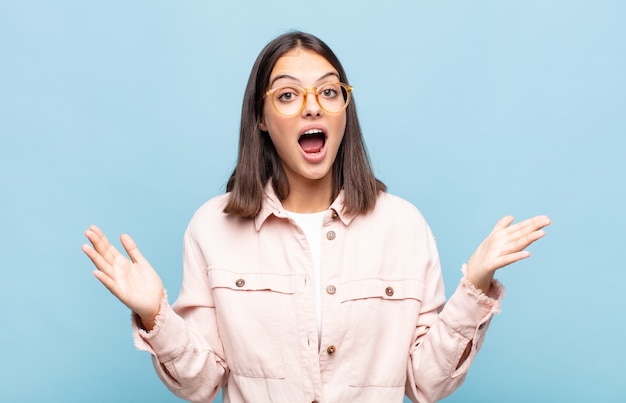 Mujer bonita joven que se siente feliz, emocionada, sorprendida o consternada