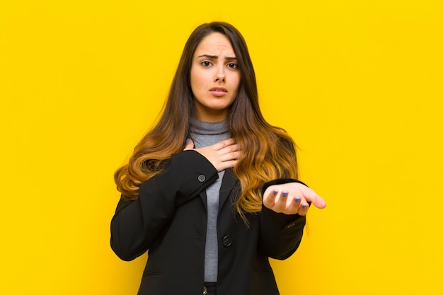 Mujer bonita joven que se siente feliz y enamorada, sonriendo con una mano al lado del corazón y la otra estirada frente al concepto de trabajo o negocio