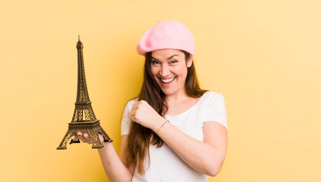 Mujer bonita joven que se siente feliz y enfrenta un desafío o celebra el concepto de parís