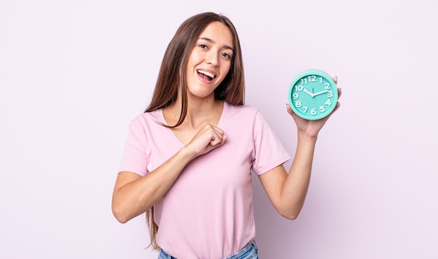 Mujer bonita joven que se siente feliz y enfrenta un desafío o celebrando. concepto de reloj despertador