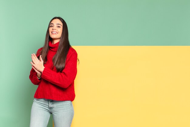 Mujer bonita joven que se siente feliz y exitosa, sonriendo y aplaudiendo, diciendo felicitaciones con un aplauso.