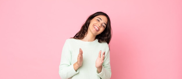 Mujer bonita joven que se siente feliz y exitosa, sonriendo y aplaudiendo, diciendo felicitaciones con un aplauso