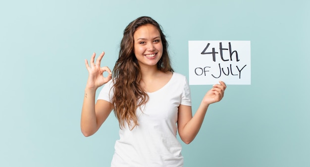 Mujer bonita joven que se siente feliz, mostrando aprobación con gesto bien concepto del día de la independencia