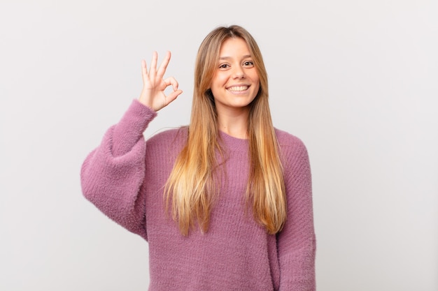 Mujer bonita joven que se siente feliz, mostrando aprobación con gesto bien