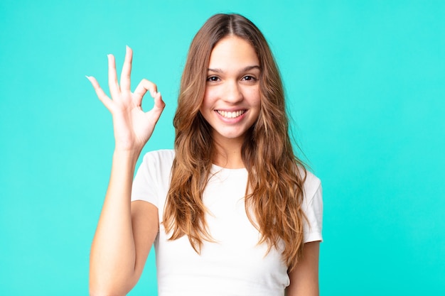 Mujer bonita joven que se siente feliz, mostrando aprobación con gesto bien