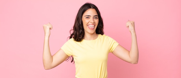 Mujer bonita joven que se siente feliz, positiva y exitosa, celebrando la victoria, los logros o la buena suerte