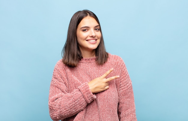 Mujer bonita joven que se siente feliz, positiva y exitosa, con la mano haciendo forma de v sobre el pecho, mostrando la victoria o la paz