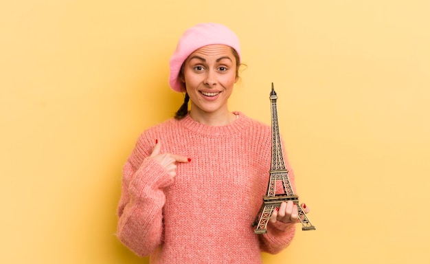 Mujer bonita joven que se siente feliz y se señala a sí misma con un concepto emocionado de París