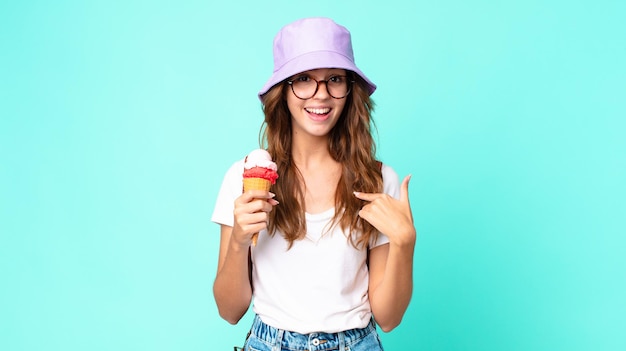 Mujer bonita joven que se siente feliz y se señala a sí misma con un emocionado sosteniendo un helado. concepto de verano