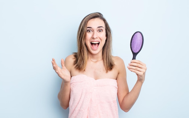 Mujer bonita joven que se siente feliz, sorprendida al darse cuenta de una solución o idea. concepto de cepillo para el cabello