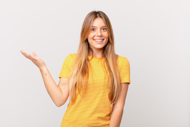 Mujer bonita joven que se siente feliz, sorprendida al darse cuenta de una solución o idea