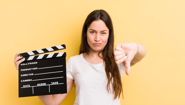 Foto mujer bonita joven que se siente mostrando los pulgares hacia abajo concepto de badajo de cine