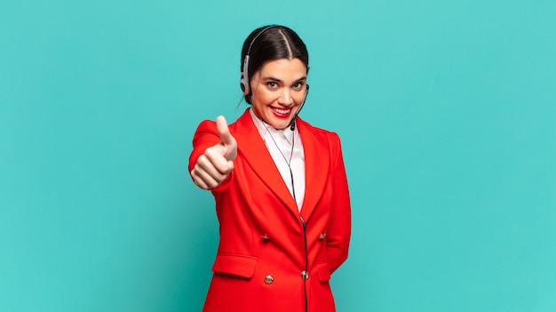 Mujer bonita joven que se siente orgullosa, despreocupada, segura y feliz, sonriendo positivamente con los pulgares hacia arriba. concepto de telemarketer