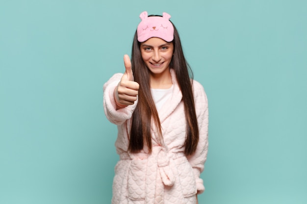 Mujer bonita joven que se siente orgullosa, despreocupada, segura y feliz, sonriendo positivamente con los pulgares hacia arriba