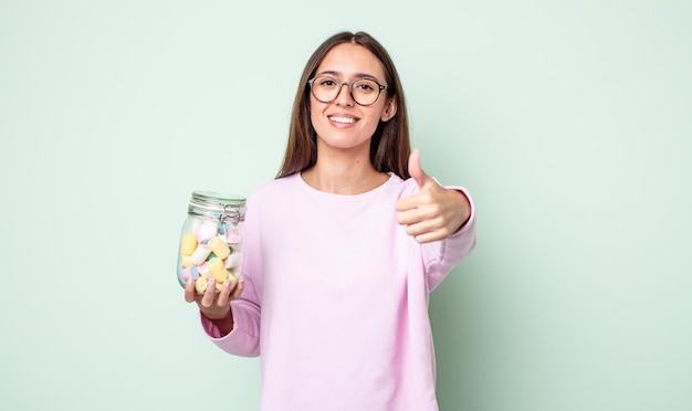 Mujer bonita joven que se siente orgullosa, sonriendo positivamente con los pulgares hacia arriba. concepto de caramelos de gelatina