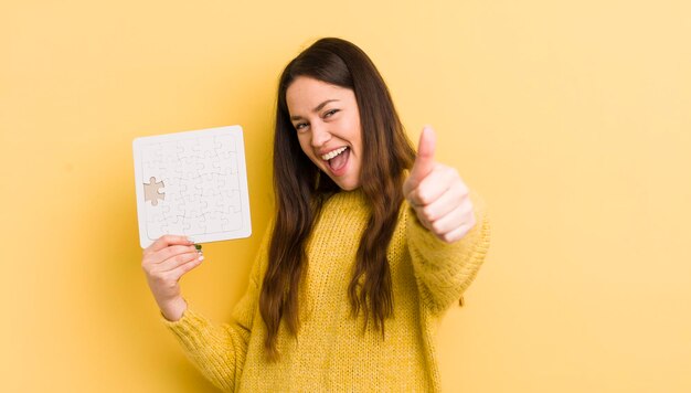 Mujer bonita joven que se siente orgullosa sonriendo positivamente con los pulgares hacia arriba concepto de rompecabezas