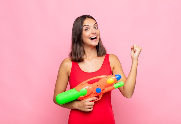 Mujer bonita joven que se siente sorprendida, emocionada y feliz, riendo y celebrando el éxito, diciendo ¡guau !. concepto de verano