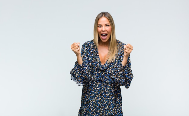 Mujer bonita joven que se siente sorprendida, emocionada y feliz, riendo y celebrando el éxito, diciendo ¡guau!