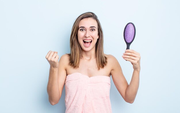 mujer bonita joven que se siente sorprendida, riendo y celebrando el éxito. concepto de cepillo para el cabello