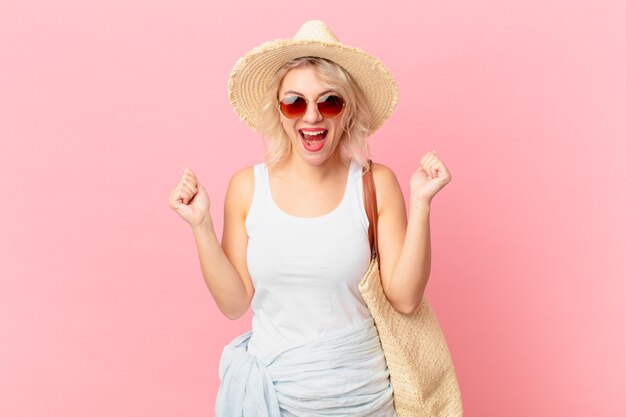 Foto mujer bonita joven que se siente sorprendida, riendo y celebrando el éxito. concepto de turismo de verano