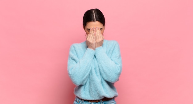 Mujer bonita joven que se siente triste, frustrada, nerviosa y deprimida, cubriendo la cara con ambas manos, llorando