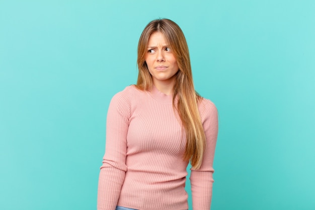 Mujer bonita joven que se siente triste, molesta o enojada y mirando hacia un lado