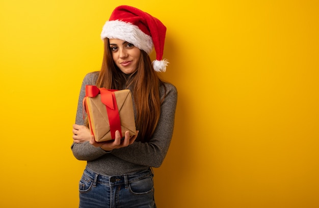 Mujer bonita joven que sostiene los brazos de la travesía del regalo, sonriendo y relajado