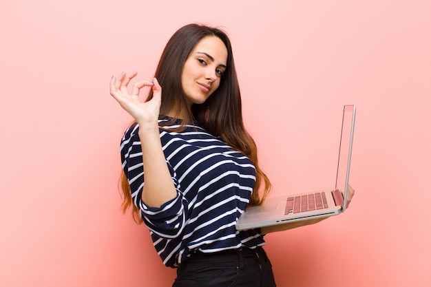 Mujer bonita joven que sostiene una computadora portátil