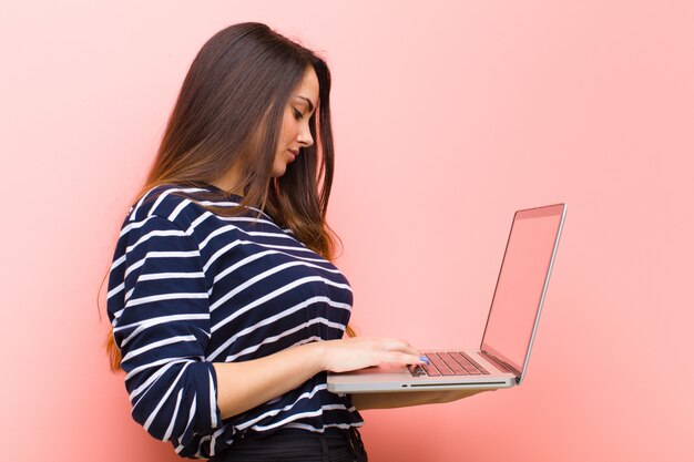 Mujer bonita joven que sostiene una computadora portátil