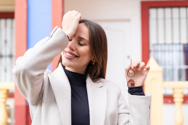 Mujer bonita joven que sostiene las llaves de casa al aire libre se ha dado cuenta de algo y tiene la intención de encontrar la solución