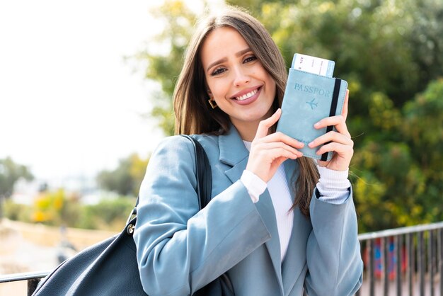 Mujer bonita joven que sostiene un pasaporte al aire libre