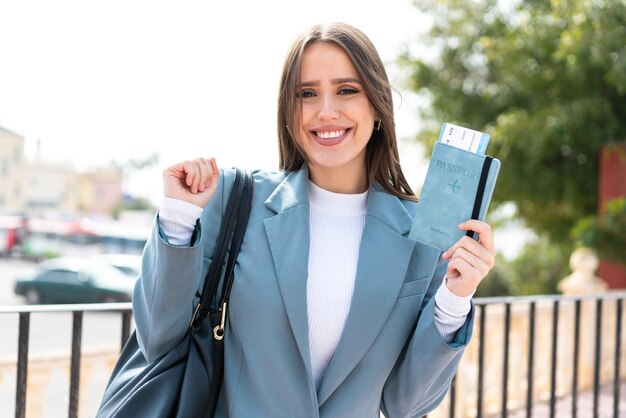 Mujer bonita joven que sostiene un pasaporte al aire libre