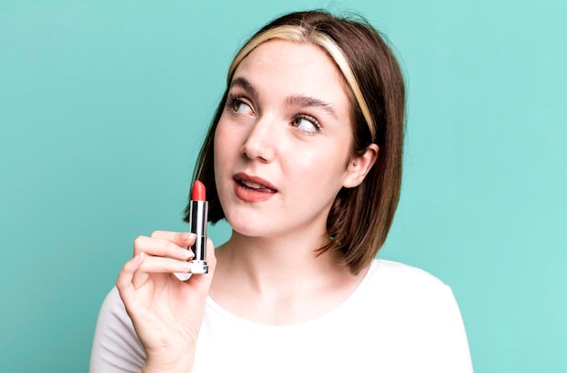 Mujer bonita joven que usa una barra de lápiz labial que compone el concepto