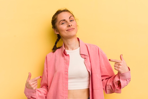 Mujer bonita joven que se ve orgullosa, arrogante, feliz, sorprendida y satisfecha, señalando que se siente como una ganadora