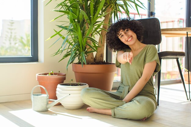 Mujer bonita joven con una regadera y plantas