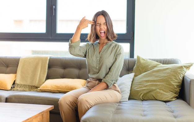 Mujer bonita joven relajándose en casa en un sofá